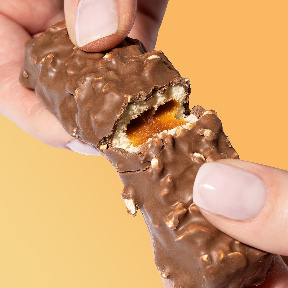 FilledProteinRiegel_PeanutCaramel_06-min Filled Protein Riegel Peanut Caramel – Hände die einen zerbrochenen Riegel halten | Aldi Sports