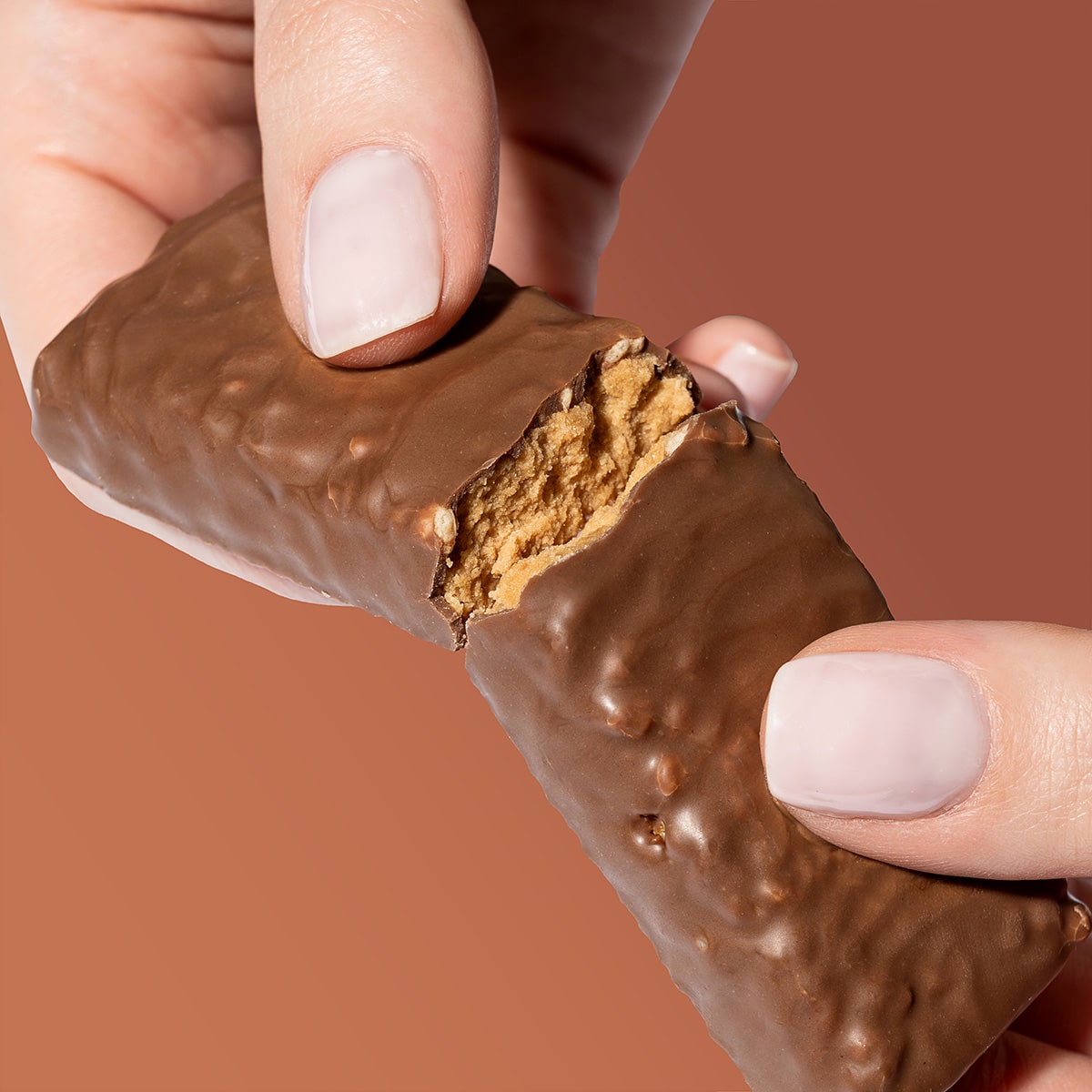 ProteinRiegel_ChocolateCaramel_06-min 50% Protein Riegel Chocolate caramel – Hände die einen zerbrochenen Riegel halten | Aldi Sports
