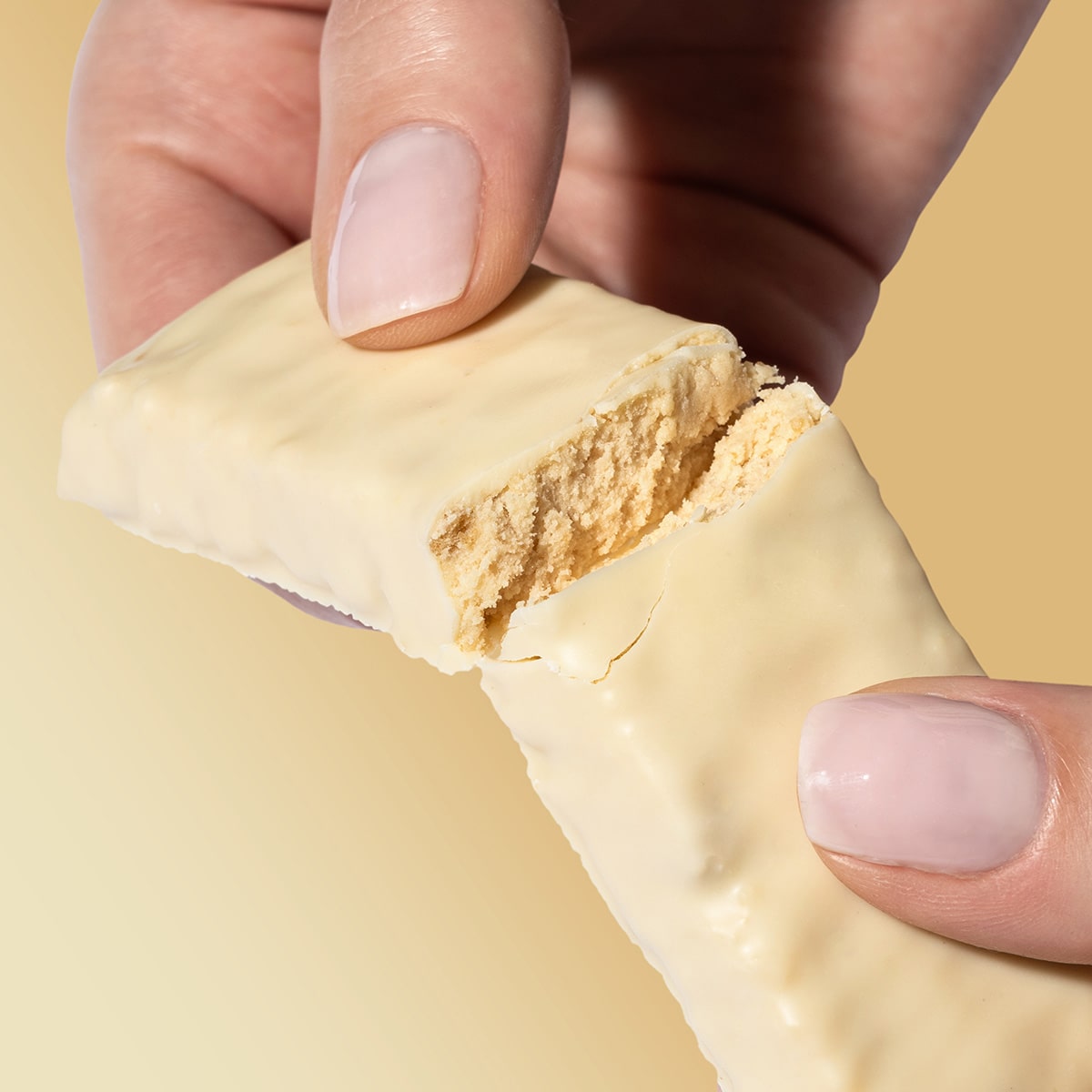 ProteinRiegel_WhiteChocolateCrisp_06-min 50% Protein Riegel White Chocolate Crisp – Zwei Hände brechen den Riegel in der Mitte | Aldi Sports