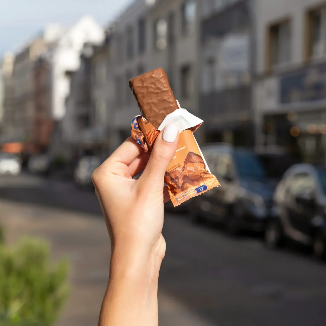 ProteinRiegel_Brownie_05 50% Protein Riegel Chocolate Caramel – Eine Hand hält den geöffneten Riegel | Aldi Sports