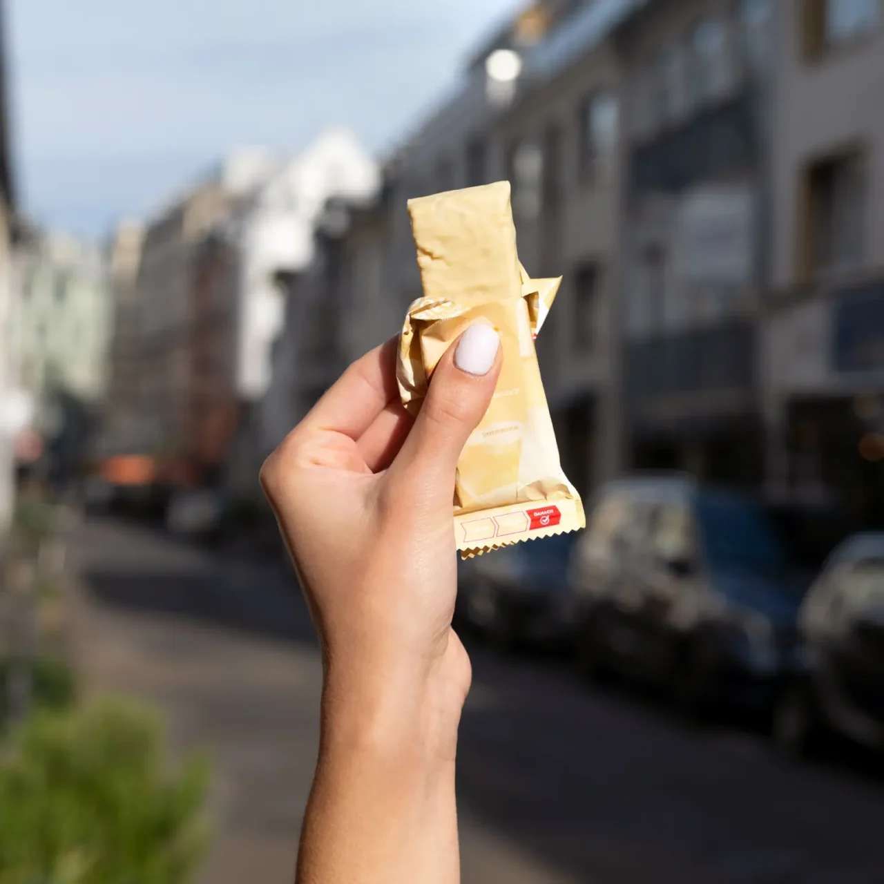 ProteinRiegel_WhiteChocolateCrisp_05 50% Protein Riegel Chocolate Caramel – Eine Hand hält den geöffneten Riegel | Aldi Sports