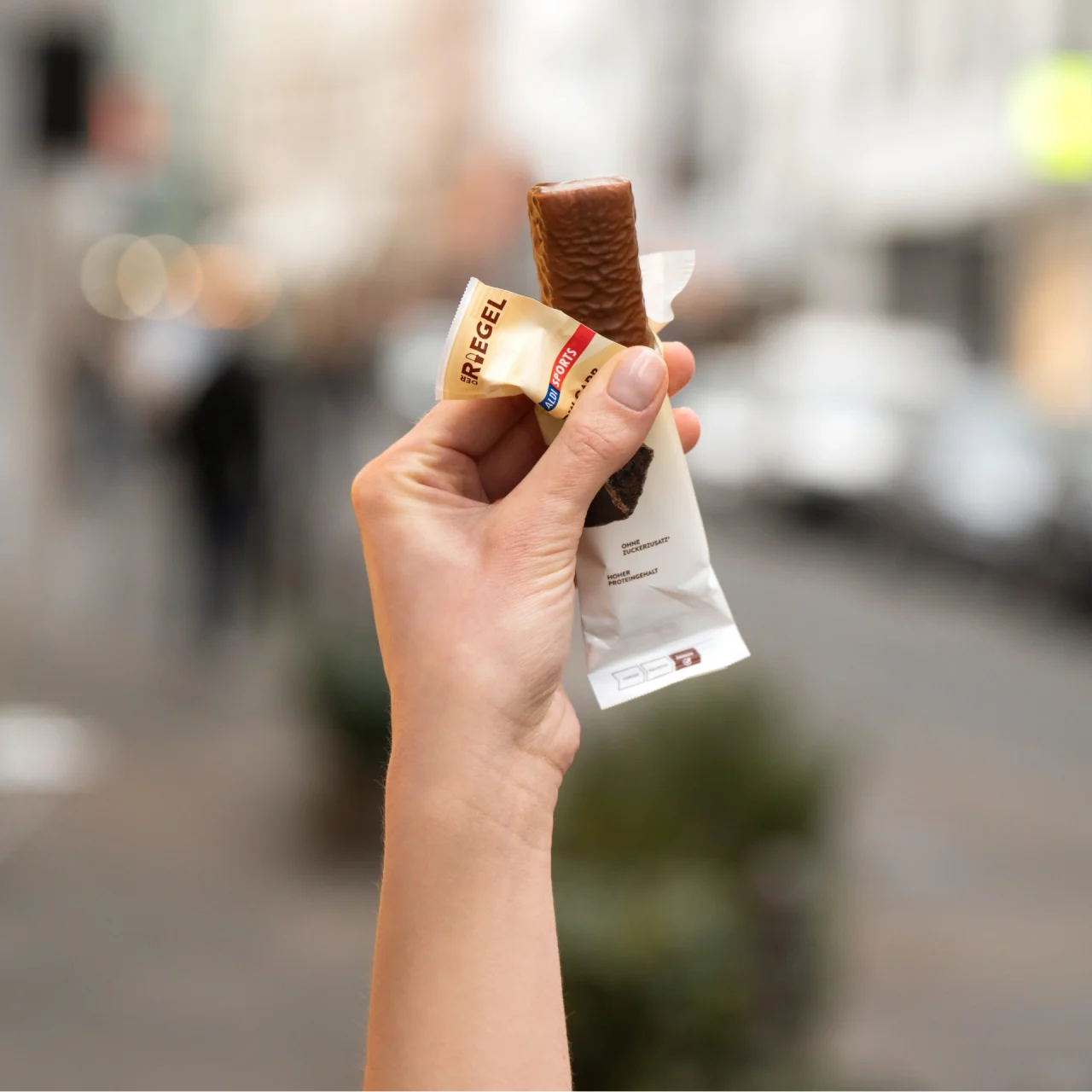 20240308_ALDI_010 (1) Lower Carb Protein Riegel Cookie & Cream – Eine Hand hält den geöffneten Riegel | Aldi Sports