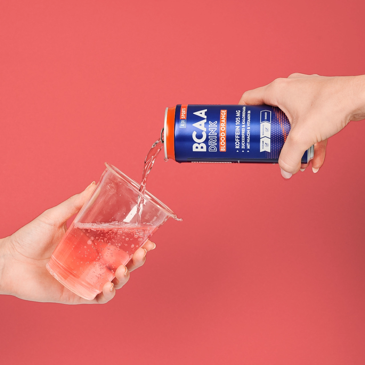 BCAA Drink Blood Orange_04 BCAA Drink Blood Orange – Flüssigkeit wird aus der Dose in einen Becher geschüttet | Aldi Sports