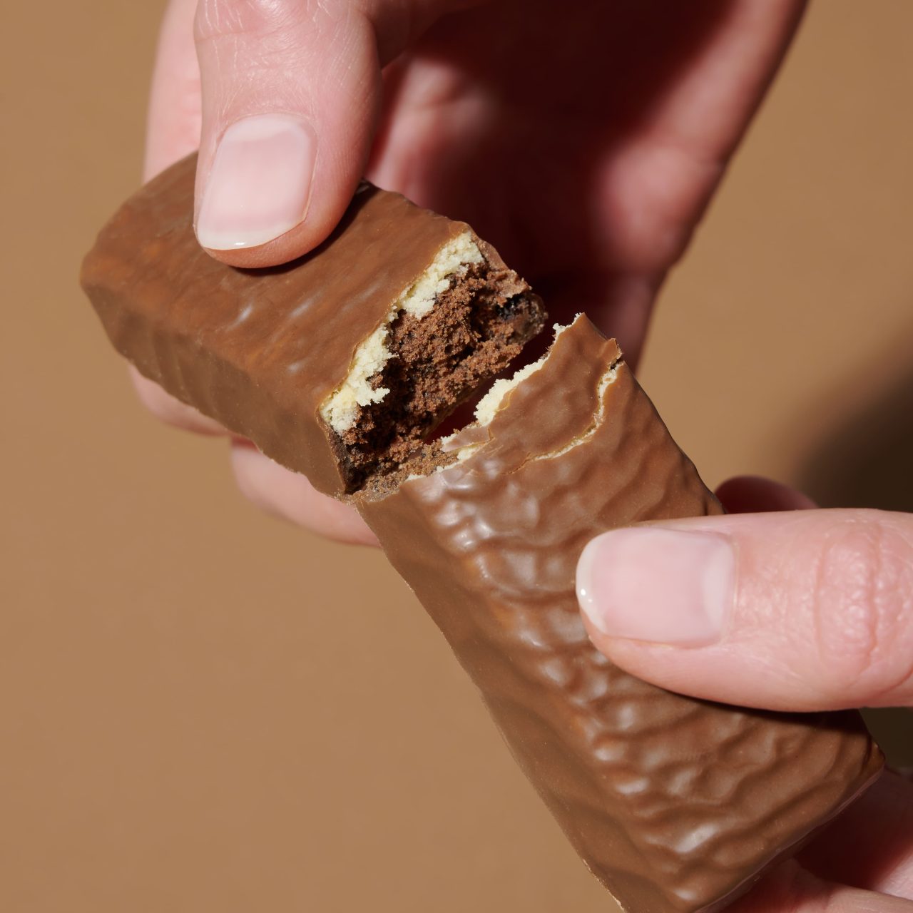 ProteinRiegelCookies&Cream_04 Lower Carb Protein Riegel Cookie & Cream – Hände die einen zerbrochenen Riegel halten | Aldi Sports