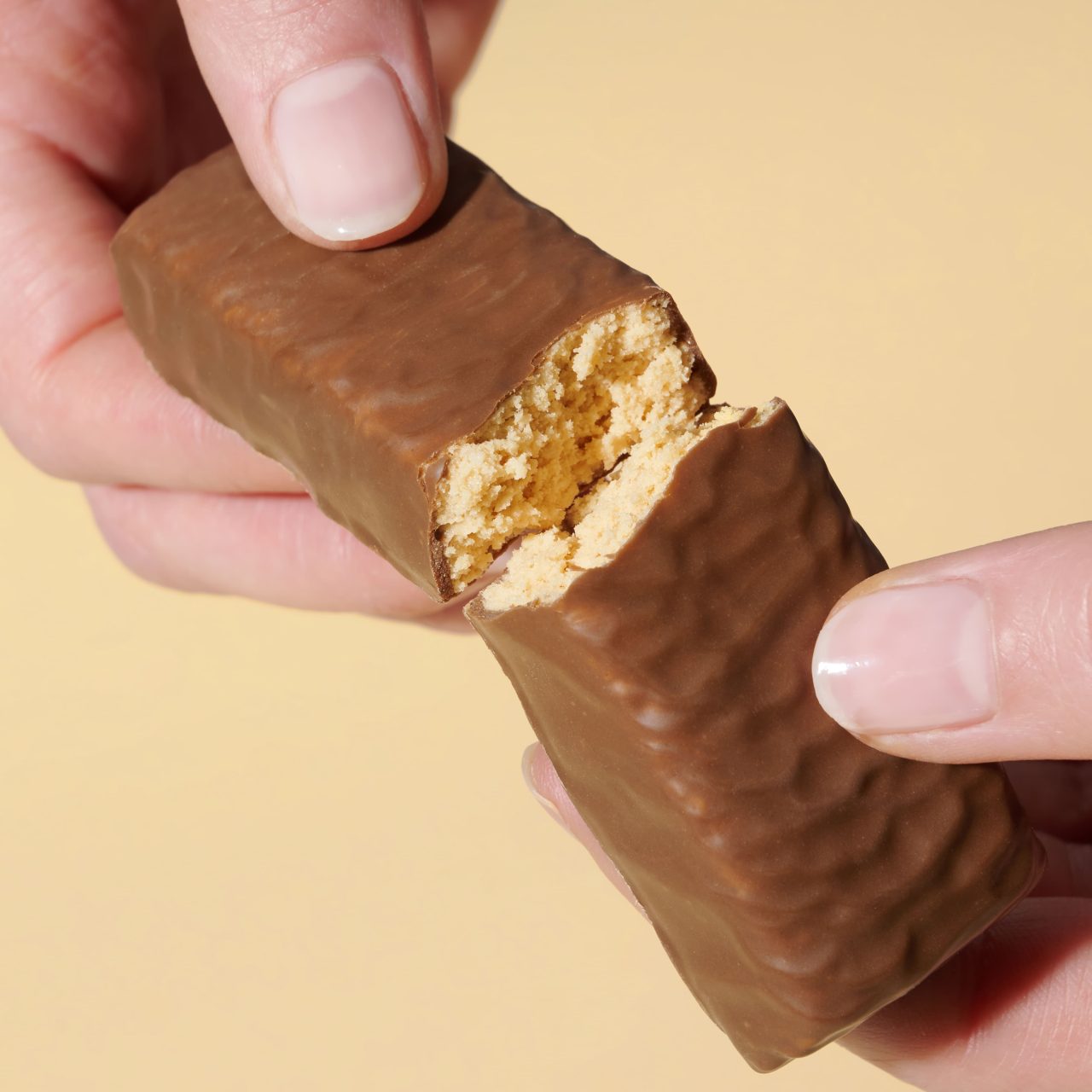 ProteinRiegelKokosMandel_04 Lower Carb Protein Riegel Kokos Mandel – Hände die einen zerbrochenen Riegel halten | Aldi Sports